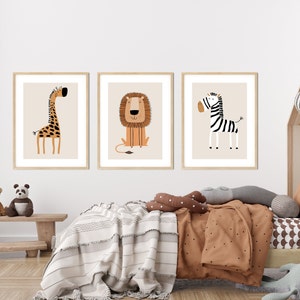 May include: Three framed illustrations of animals in a nursery setting. The illustrations are of a giraffe, a lion, and a zebra. The illustrations are in a minimalist style with simple lines and bright colors.
