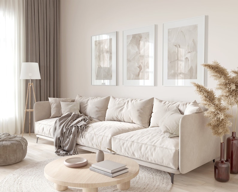 May include: A white sectional sofa with a throw blanket and cushions in a living room with a wooden coffee table, a lamp, and a vase of dried pampas grass.