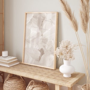 May include: A light wood bench with a woven rattan top, two woven baskets, and a white vase with dried white flowers. A framed abstract painting with a beige background hangs on the wall behind the bench.
