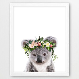May include: A cute koala wearing a flower crown with pink, white, and yellow flowers. The koala is looking directly at the camera with a sweet expression.