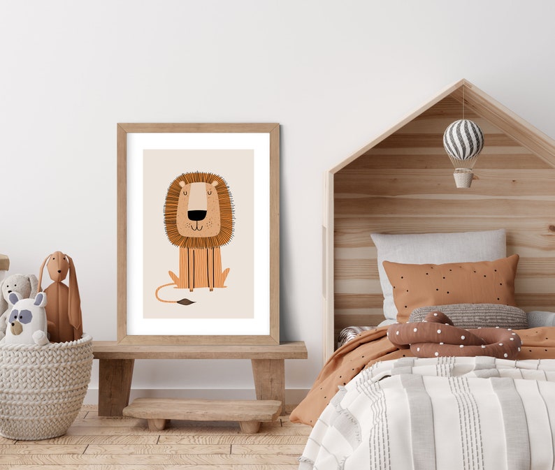May include: A framed print of a cartoon lion with a brown mane and a light brown body. The lion is sitting with its paws crossed and has a friendly expression. The print is on a white background and is framed in a light brown wood frame.