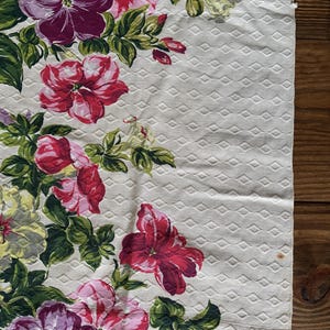 K&ouml;nnte beinhalten: Ein floraler Stoff mit einem sich wiederholenden Rautenmuster. Er zeigt gro&szlig;e, farbenfrohe Blumen in Rot, Rosa und Lila mit gr&uuml;nen Bl&auml;ttern. Die Blumen sind in einem Kaskaden-Design angeordnet und schaffen einen ansprechenden Textil.