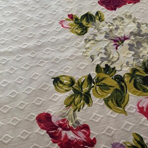 K&ouml;nnte beinhalten: Cremefarbener Stoff mit Rautenmuster und floralem Design. Die Blumen sind in Rot-, Rosa-, Gr&uuml;n- und Wei&szlig;t&ouml;nen gehalten. Der Stoff hat eine strukturierte Optik.