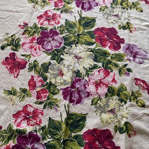 K&ouml;nnte beinhalten: Cremefarbener Blumenstoff mit einem sich wiederholenden Rautenmuster. Er zeigt gro&szlig;e Bl&uuml;ten in Rot, Rosa, Lila und Wei&szlig; mit gr&uuml;nen Bl&auml;ttern. Das Design ist ein klassisches Blumenmuster, geeignet f&uuml;r verschiedene Textilanwendungen.