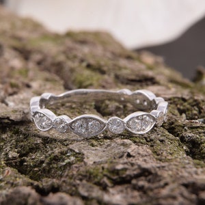 Pode incluir: Um anel de banda de prata com uma fila de diamantes de forma oval engastados em um design festoneado.