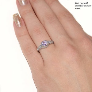 May include: A silver-toned ring featuring a round, light purple amethyst as the main stone, surrounded by small clear accent stones along the band. The text "This ring with amethyst as main stone" is visible in the upper right corner of the image.