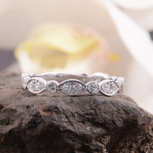 Pode incluir: Uma banda de prata delicada com uma fila de pequenos diamantes redondos e ovais engastados em um design festoneado.