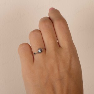 Puede incluir: Un anillo de plata con una sola piedra preciosa transparente engastada en una banda retorcida.