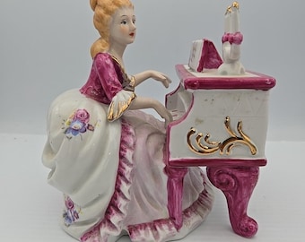 Figura de porcelana de una dama victoriana con encaje vienés tocando el piano.