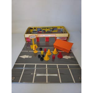 Könnte beinhalten: Ein Vintage Sears Service Center Spielset mit einer faltbaren Straßenmatte, einem Gebäude mit DieHard-Schild, einem Sears-Schild, einem orangefarbenen Dachteil sowie verschiedenen Miniatur-Verkehrskegeln, Reifen und kleinen roten und gelben Fässern.