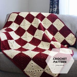 Könnte beinhalten: Handgefertigte Häkeldecke in einem Schachbrettmuster aus cremefarbenen und burgunderfarbenen Quadraten. Die Decke ist über ein graues Sofa drapiert. Der Text "CROCHET PATTERN" und "Instant Download" ist sichtbar.