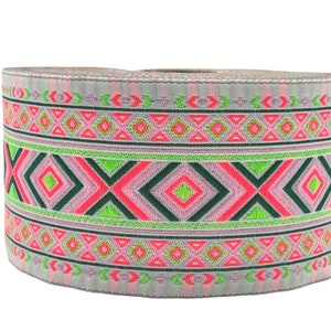 May include: A roll of pink, green, and black patterned trim with a geometric design. The trim is woven with a silver thread.