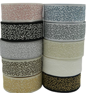 May include: A stack of ten rolls of decorative trim with a leaf pattern. The trim is available in a variety of colours, including black, white, grey, beige, pink, blue, and gold.