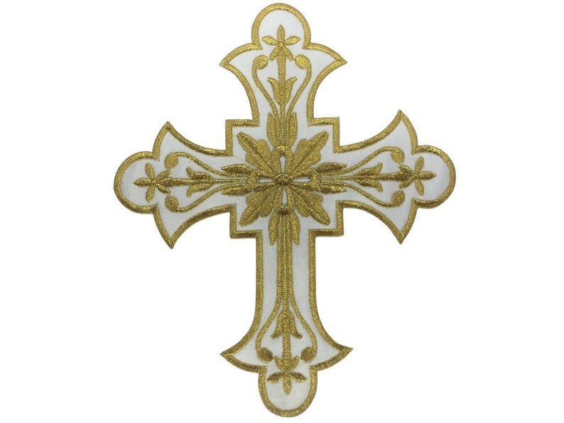 Może przedstawiać: Biały krzyż z haftem złotym. Krzyż ma kwiatowy wz&oacute;r i jest symbolem religijnym.