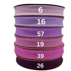 May include: Six spools of purple fabric ribbon stacked on top of each other. The spools are labeled with the numbers 6, 16, 57, 19, 39, and 26.