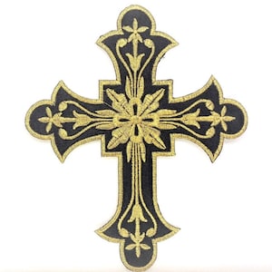 Może przedstawiać: Czarny haftowany krzyż z złotymi kwiatowymi detalami. Krzyż jest symbolem religijnym, często używanym w sztuce i dekoracji chrześcijańskiej.