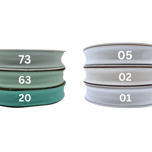 May include: Three rolls of fabric ribbon in different shades of green and white. The rolls are labeled with the numbers 73, 63, 20, 05, 02, and 01.