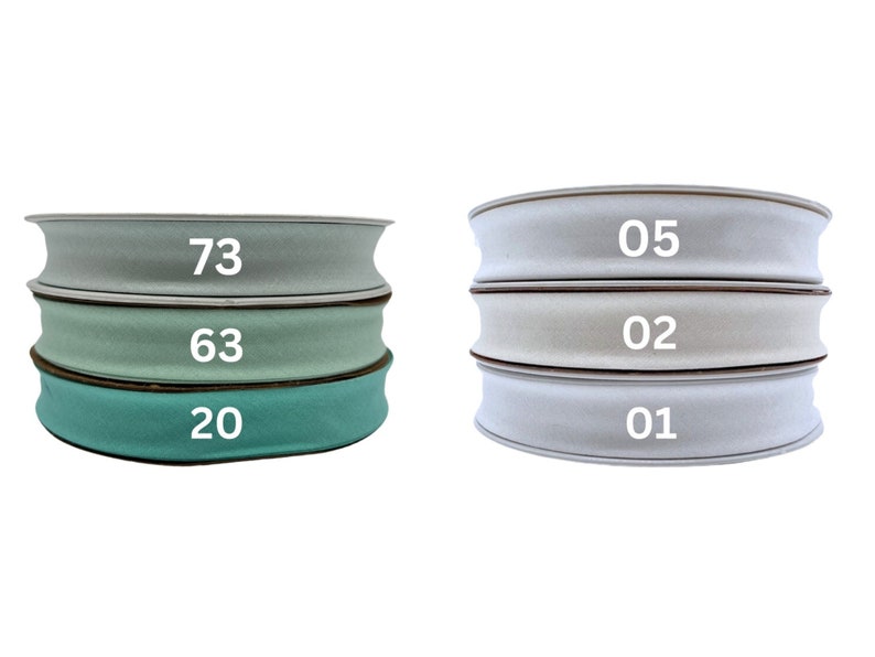 May include: Three rolls of fabric ribbon in different shades of green and white. The rolls are labeled with the numbers 73, 63, 20, 05, 02, and 01.
