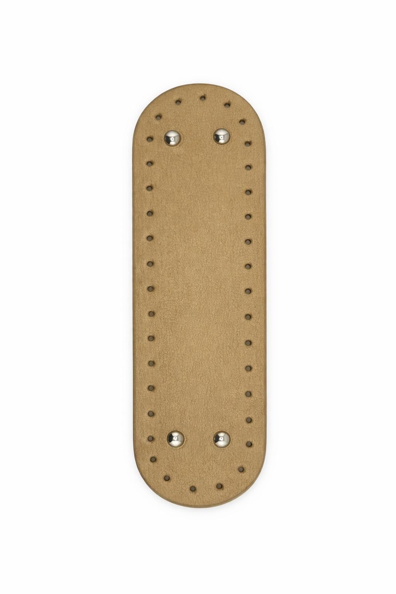 Op de afbeelding: Een langwerpige, ovale, beige basis met afgeronde uiteinden, voorzien van een reeks gelijkmatig verdeelde, voorgeponste gaten langs de gehele omtrek. Vier gepolijste, zilverkleurige metalen klinknagels zijn bevestigd nabij de randen.