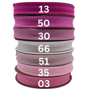 May include: A stack of seven pink and purple fabric ribbon rolls with numbers 13, 50, 30, 66, 51, 35, and 03 printed on them.