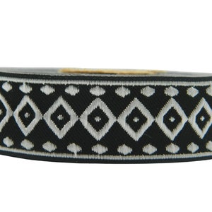 May include: Black and white trim with a geometric diamond pattern. The trim is woven with a white thread on a black background.