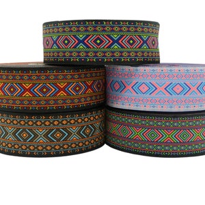 Può includere: Quattro rotoli di passamaneria colorata con motivi geometrici in tonalità di rosso, blu, verde, arancione, rosa e nero.
