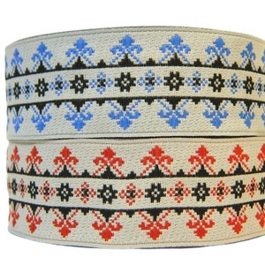 Può includere: Due rotoli di passamaneria elastica beige con motivi geometrici neri, rossi e blu. La passamaneria ha un aspetto tessuto.