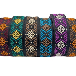 May include: Six spools of black ribbon with colourful embroidered patterns. The patterns are geometric and feature a repeating design of flowers and leaves. The ribbons are arranged in a stack, with the top ribbon being orange, followed by yellow, brown, blue, purple, and brown.