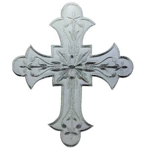 Może przedstawiać: Srebrny haftowany krzyż z misternymi wzorami kwiatowymi. Krzyż jest symbolem religijnym, często używanym w sztuce i dekoracji chrześcijańskiej.