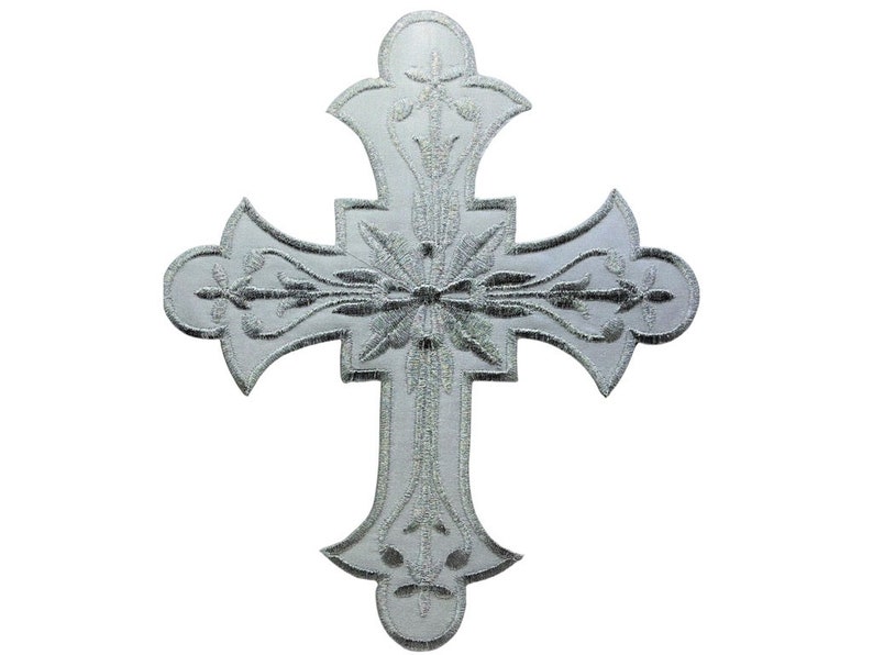 Może przedstawiać: Srebrny haftowany krzyż z misternymi wzorami kwiatowymi. Krzyż jest symbolem religijnym, często używanym w sztuce i dekoracji chrześcijańskiej.