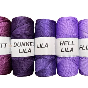 May include: Five spools of thread in shades of purple, violet, and lavender. The spools are labeled "Violett", "Dunkel Lila", "Lila", "Hell Lila", and "Flieder".