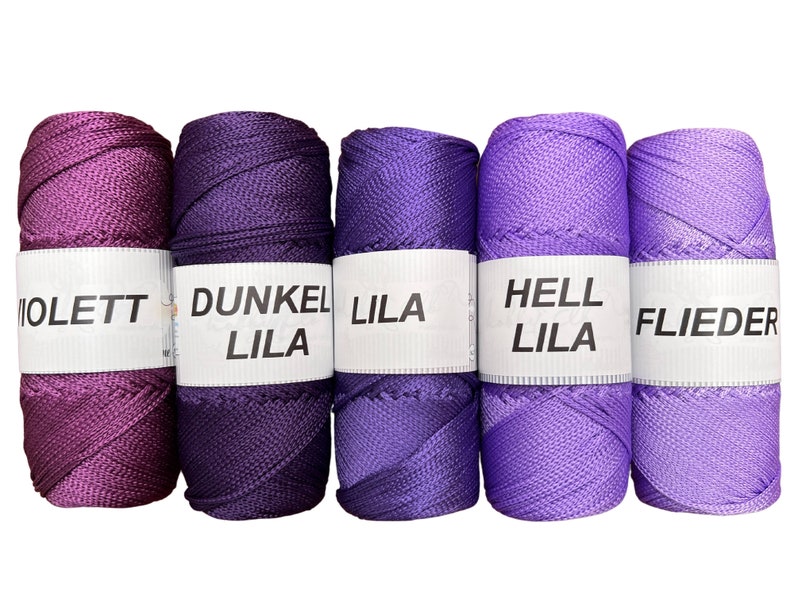 May include: Five spools of thread in shades of purple, violet, and lavender. The spools are labeled "Violett", "Dunkel Lila", "Lila", "Hell Lila", and "Flieder".
