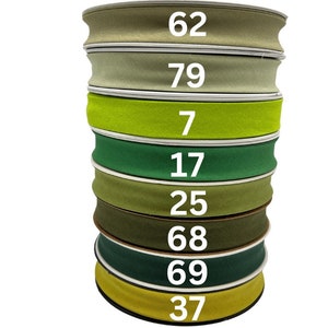 May include: A stack of eight green, yellow, and brown fabric ribbon rolls with numbers printed on each roll. The numbers are 62, 79, 7, 17, 25, 68, 69, and 37.