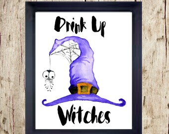 May include: A framed Halloween-themed print featuring a purple witch hat with a spider web and a dangling spider. The text "Drink Up Witches" is written in black script, perfect for spooky decor.