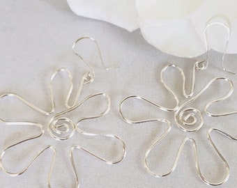 May include: A pair of silver dangle earrings with a flower design. The earrings are made of wire and have a spiral in the center of the flower.