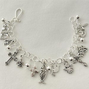 Pu&ograve; includere: Un braccialetto con ciondoli d'argento con simboli religiosi. I ciondoli includono croci, angeli, una colomba e un pesce con la parola "Ges&ugrave;". Il braccialetto &egrave; fatto di catene e ha una chiusura a gancio.