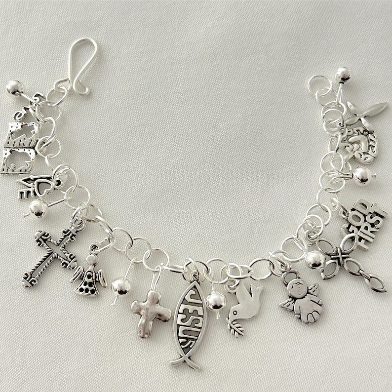 Pu&ograve; includere: Un braccialetto con ciondoli d'argento con simboli religiosi. I ciondoli includono croci, angeli, una colomba e un pesce con la parola "Ges&ugrave;". Il braccialetto &egrave; fatto di catene e ha una chiusura a gancio.