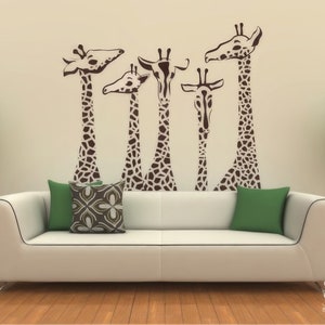 May include: A white couch with two green and one brown patterned pillows in front of a wall with a brown giraffe family silhouette decal.
