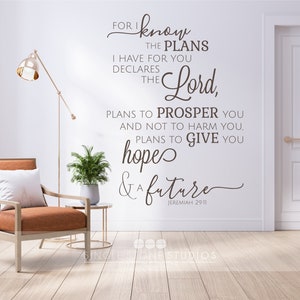 Puede incluir: Interior de una habitación con una calcomanía de pared con el texto "For I know the plans I have for you declares the Lord, plans to prosper you and not to harm you, plans to give you hopes & a future." También se ven una silla, una lámpara y plantas.
