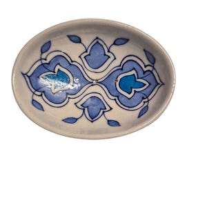 Könnte beinhalten: Ovale Keramikschale mit weißem Grund und blauem Blumenmuster. Das Design weist symmetrische Muster mit dunkel- und hellblauen Akzenten auf. Die Schale ist wahrscheinlich handgefertigt und für dekorative oder funktionale Zwecke geeignet.