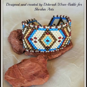 May include: A beaded bracelet with a geometric pattern in shades of blue, brown, white, and red. The bracelet is designed and created by Deborah Wear-Finkle for Shoshin Arts.