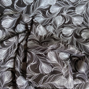 May include: Black fabric with a white feather pattern. The fabric is folded and textured.