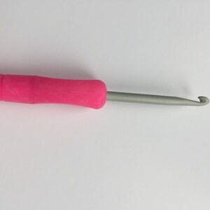 Puede incluir: Un gancho de ganchillo rosa y plateado con un agarre c&oacute;modo.