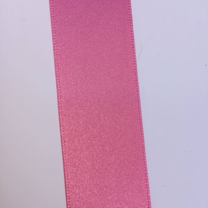 May include: A close-up of a pink satin ribbon.
