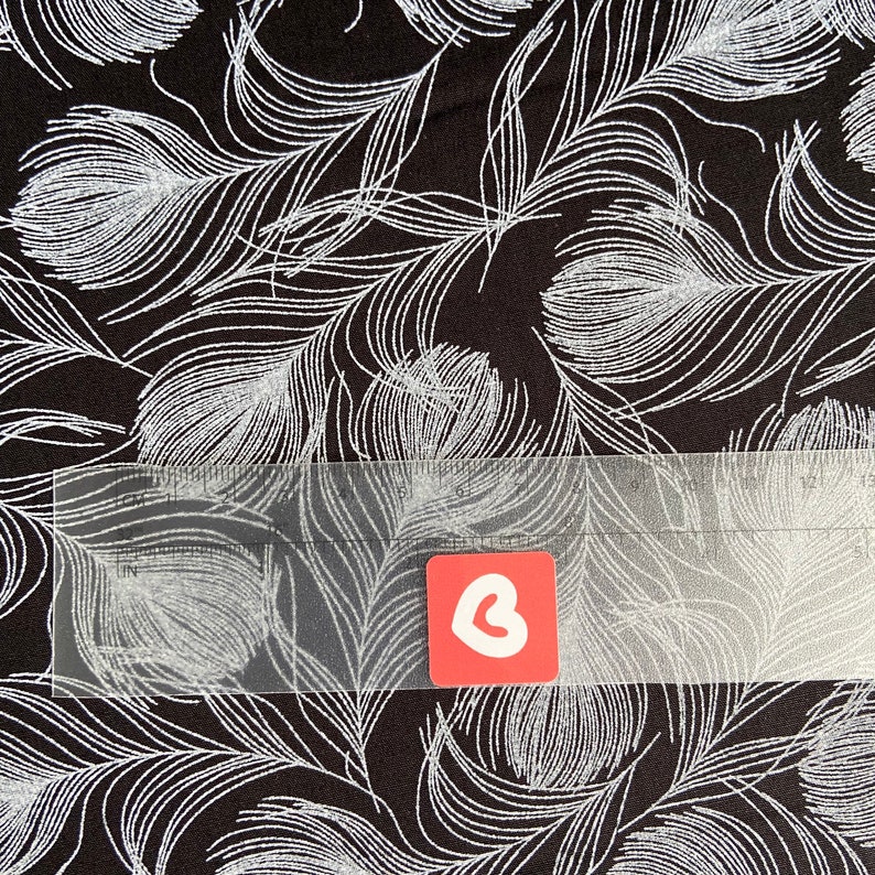 May include: Black fabric with a white feather pattern. The fabric is textured and has a subtle shimmer.