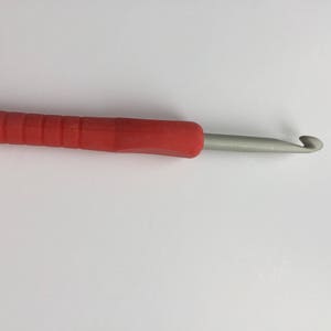 Puede incluir: Un gancho de ganchillo rojo y gris con un agarre c&oacute;modo.