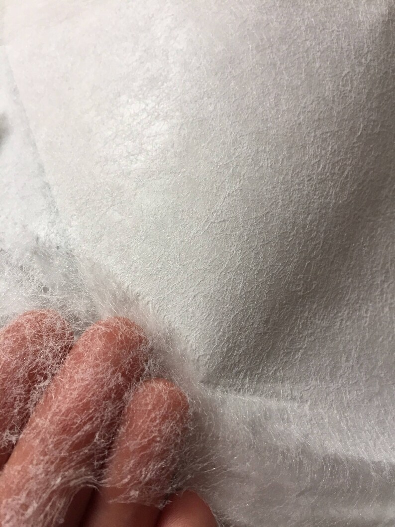 May include: White, lightweight, non-woven fabric with a textured surface. The fabric is thin and delicate, with a slightly fuzzy texture.