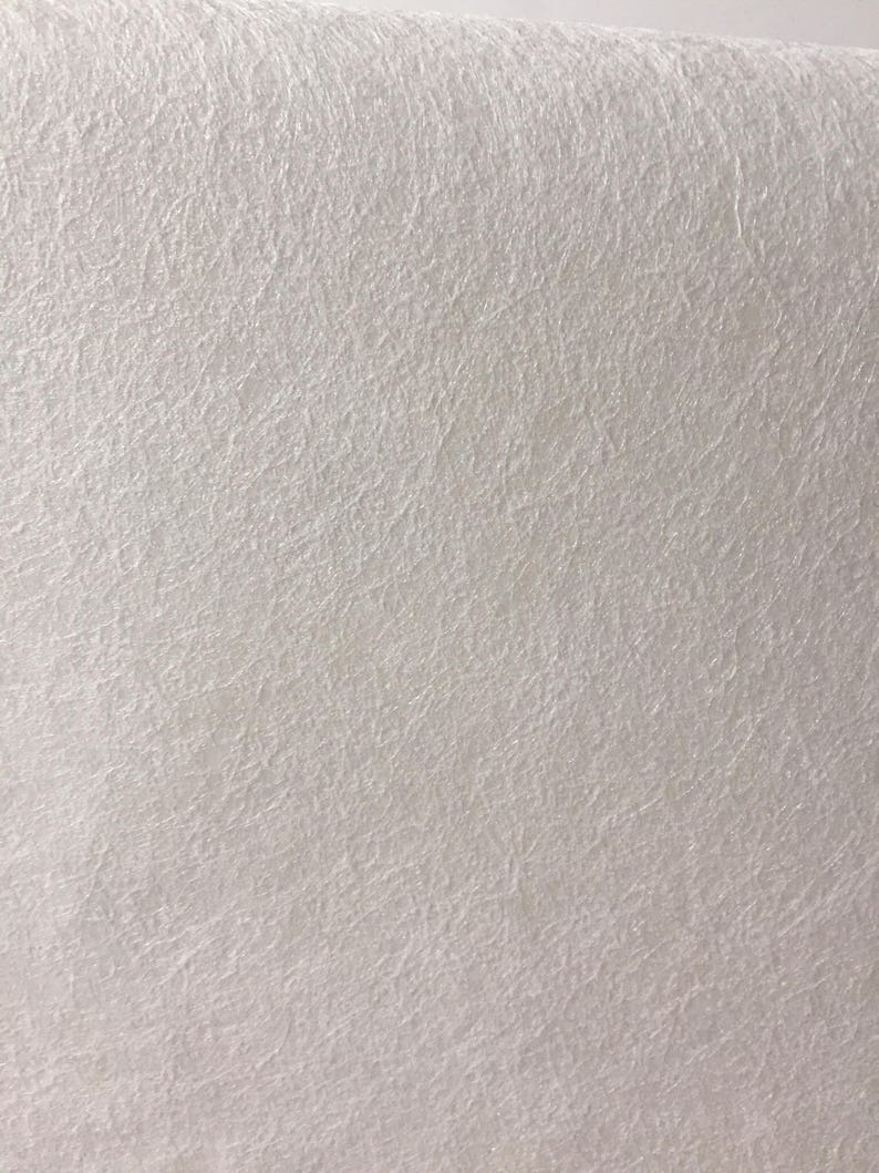 May include: Close-up of a white, textured surface. The surface has a fine, woven pattern.