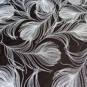May include: Black fabric with a silver glitter pattern of repeating feather designs.