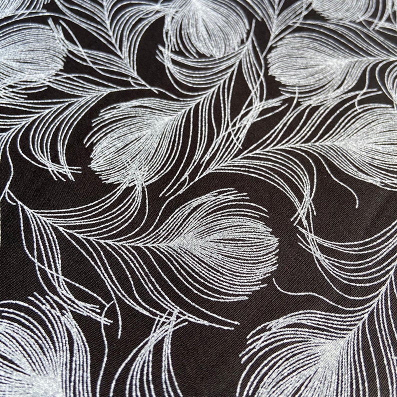 May include: Black fabric with a silver glitter pattern of repeating feather designs.